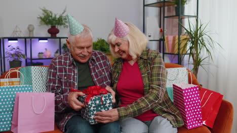 happy senior grandmother wife giving birthday gift box surprise present to her husband grandfather