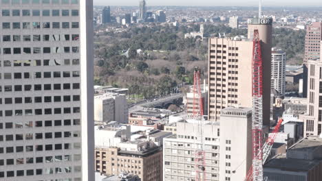 Vista-De-Lapso-De-Tiempo-Desde-La-Azotea-De-Un-Edificio-Comercial-Del-Centro-De-Cbd-Y-Grúas-De-Construcción-Con-Tranvías-Que-Pasan-Por-El-Puente