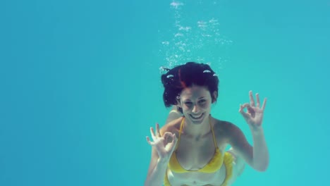 gorgeous brunette in yellow bikini swimming underwater