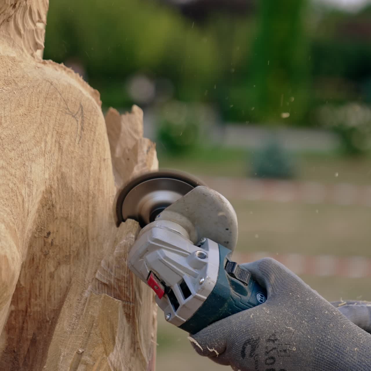 Hands of unrecognized person in gloves hold a grinding tool. Electric instrument working with piece of wood