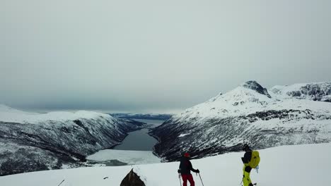 Drone-aerial-footage-two-skier-wenting-top-of-the-mountain-with-amazing-views-to-north-Norway-mountains-and-arctic-sea