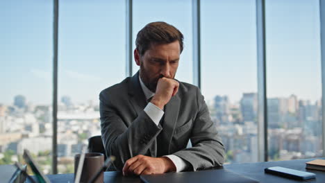 focused businessman thinking decision in panoramic office. bearded boss at desk