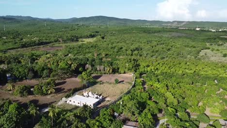 drone shot capturing rural green countryside of dominican republic revealing large mountains in the background