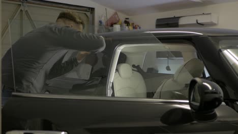 man wiping car side window tinting foil