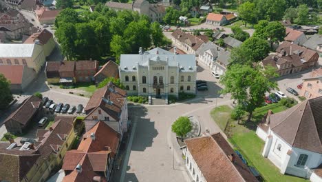 Aerial-establishing-view-of-Kuldiga-Old-Town-,-houses-with-red-roof-tiles,-sunny-summer-day,-travel-destination,-wide-drone-shot-moving-backward,-tilt-up