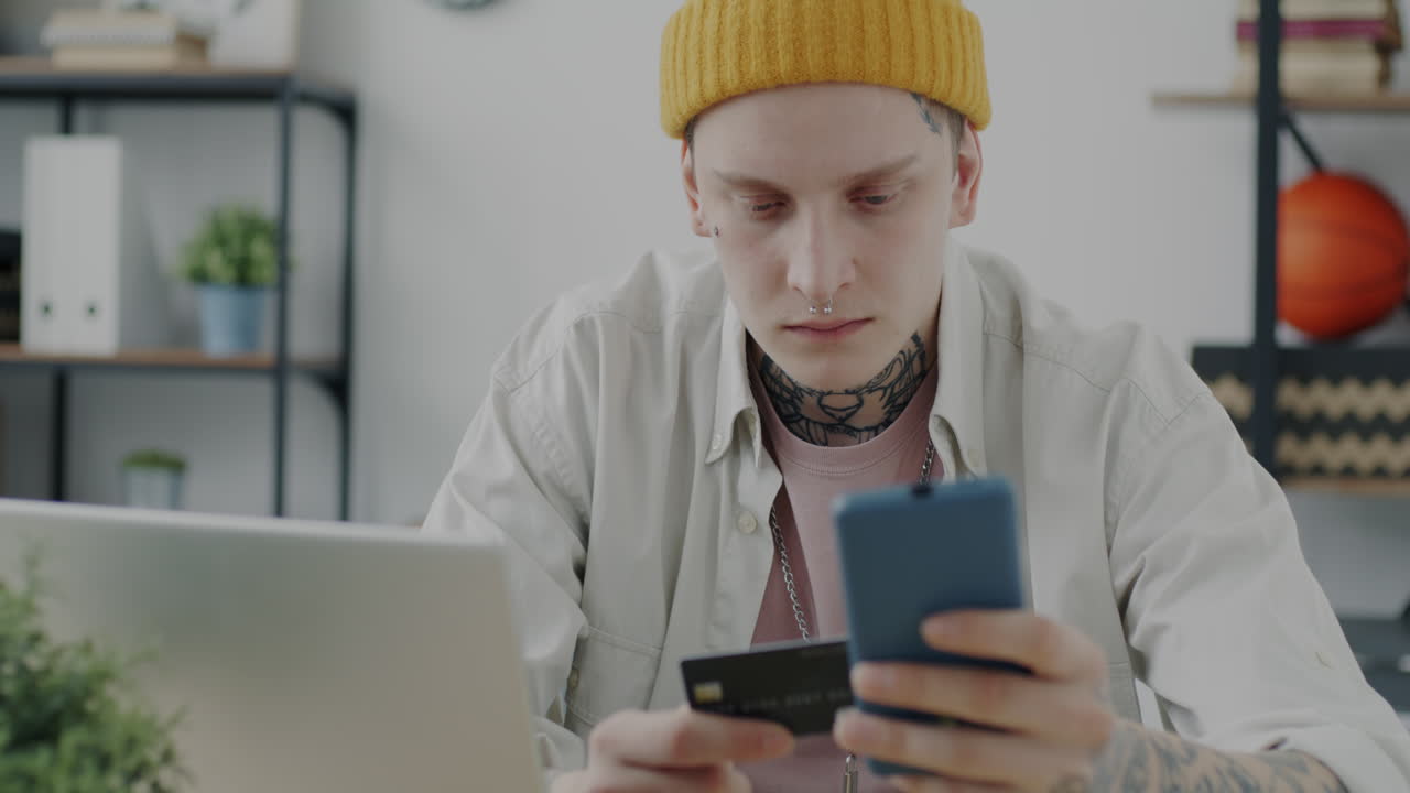 Young Man Using Mobile Phone and Credit Card for Online Shopping