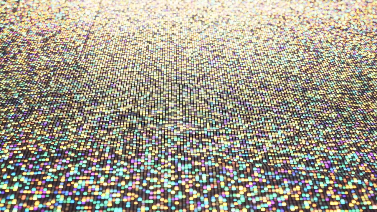 Close-up motion showing thousands of tiny rectangular iridescent tiles across flat horizontal surface, with shimmering highlights, shifting glow, soft reflections, and rich decorative color