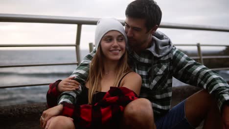 Loving-Sport-Couple-Sitting-On-Border-At-Coastline-Asphalt-Road-On-Background-Hills-And-Foggy-Ocean-1