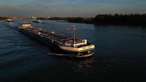 Parallex-Luftaufnahme-Des-Schiffes-Bacchus,-Das-Durch-Die-Stadt-Zwijndrecht-Segelt,-Und-Wunderschönes-Sonnenlicht,-Das-Mit-Anderen-Schiffsverkehren-Darauf-Fällt