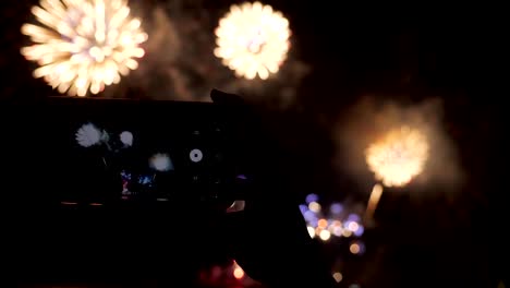 manos de una mujer grabando un espectáculo de fuegos artificiales con un teléfono inteligente