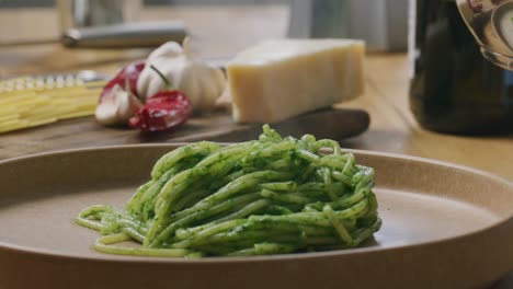 kitchen tongs twirling hot spaghetti with spinach sauce on plate