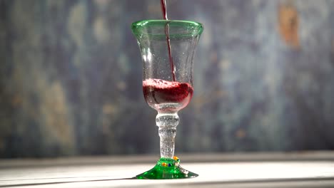 clip de vino tinto en bucle sin costuras que se vierte en un vaso rústico con fondo azul