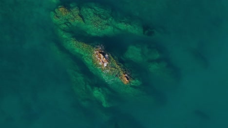 clear turquoise waters revealing rocky formations off the coast of italy, aerial view