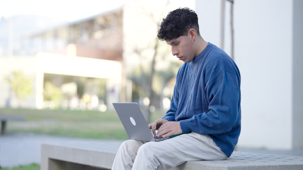 Young student experiencing frustration while working on laptop outdoors