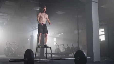 Athlete-gave-exercise.-Jumping-on-the-box.-Phase-touchdown.-Gym-shots-in-the-dark-tone.-Smoke-in-gym
