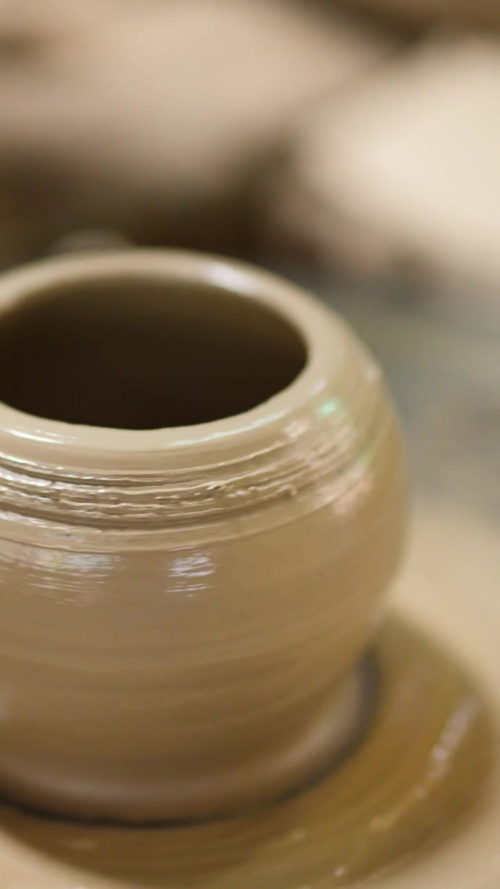 Un vaso di argilla bagnato ruota su un tornio in un laboratorio di ceramica tradizionale