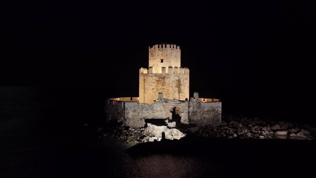 Methoni,Messenia,Peloponnese,Aerial view forward and circle pan left around the beautifully illuminated Bourtzi tower at night
