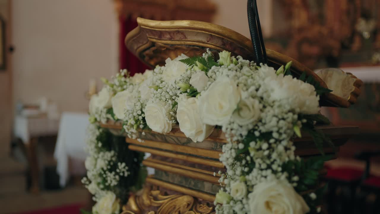 Primer plano de arreglo floral con rosas blancas que adornan el interior del púlpito de la iglesia