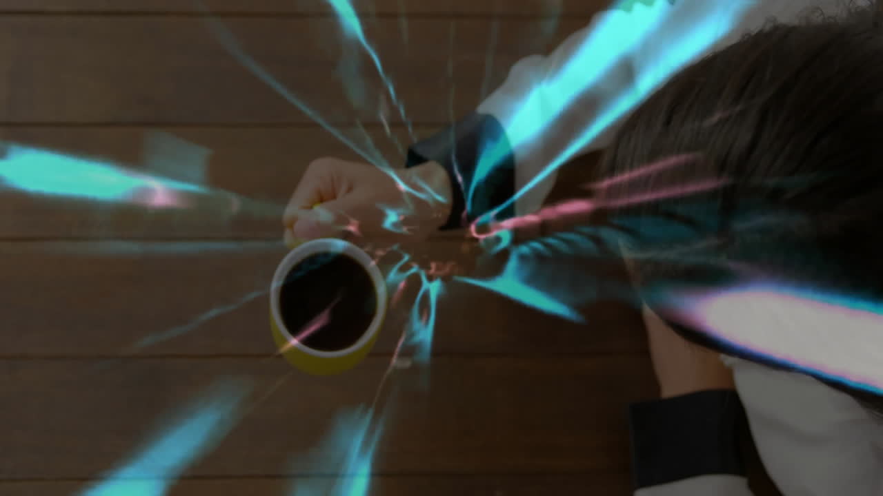 woman wearing glasses leaning over table reaching coffee mug amid blue technology light streaks