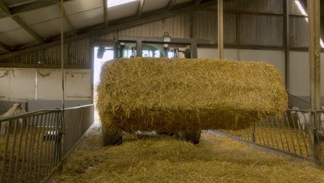 a tractor pulling into a barn with a massive block of hay