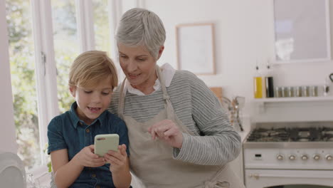 happy little boy showing grandmother how to use smartphone teaching granny modern technology intelligent child helping grandma with mobile phone at home