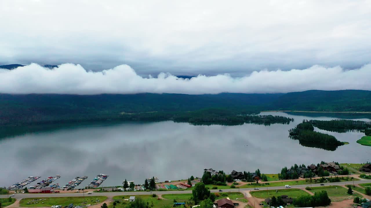 hermoso embalse de montaña de sombra con nubes de baja elevación en un día nublado de verano en grand lake colorado con coches conduciendo en la carretera a lo largo de la costa