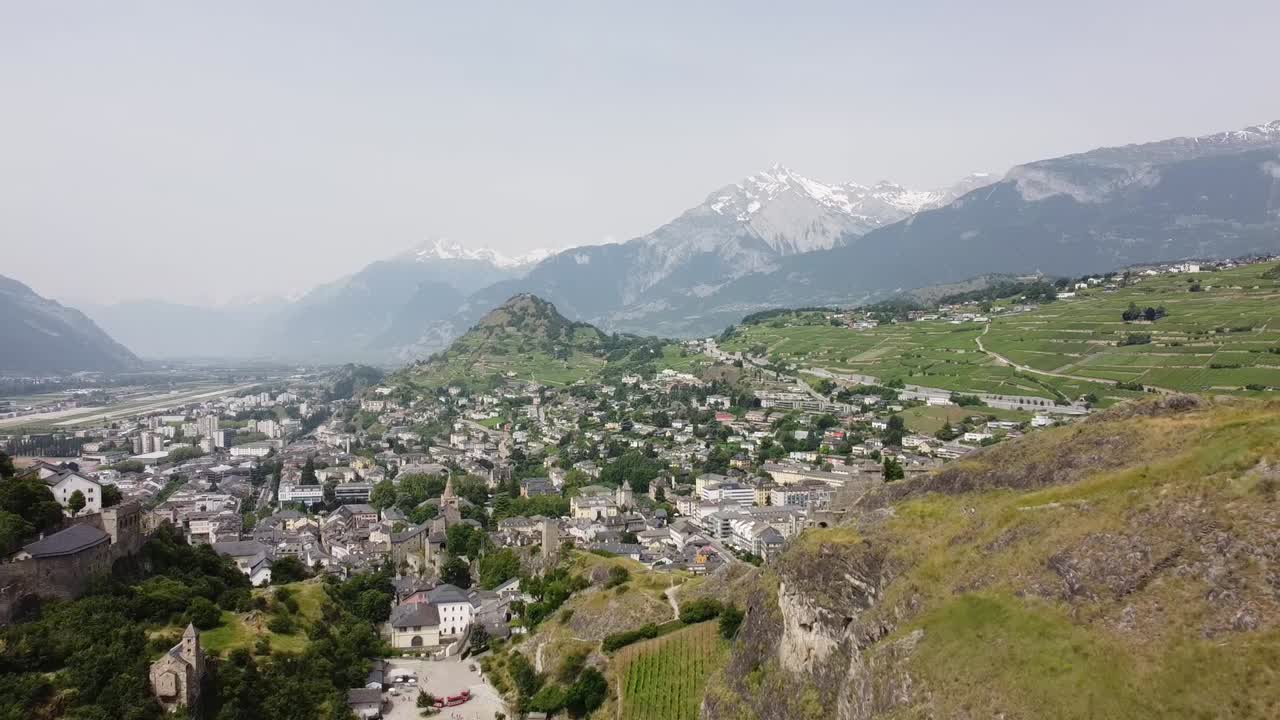 vuelo de drones entre dos colinas con castillos en la verde suiza con hermoso clima soleado