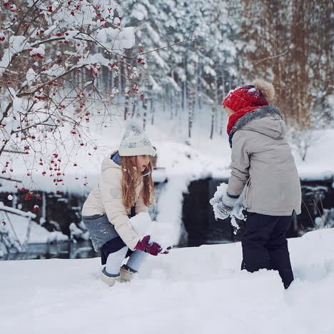 joyful children are throwing snow up on the background of winter river. little girls are playing with white snow in winter in the forest. slow motion.