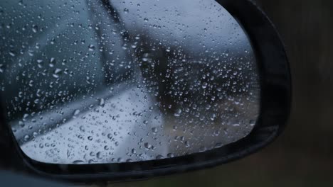 raindrops run down the glass and mirror of the car.