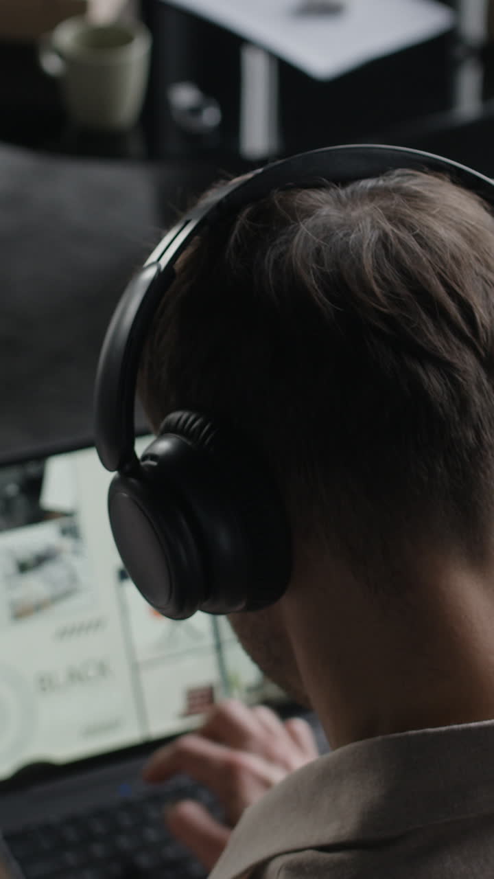 헤드폰을 들고 노트북에서 일하는 사람