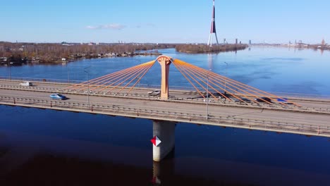 southern bridge in riga, a modern cable-stayed bridge over water with orange cables