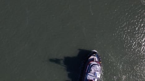 a top down, aerial view high over a tugboat on a sunny day in the east rockaway inlet in queens, ny