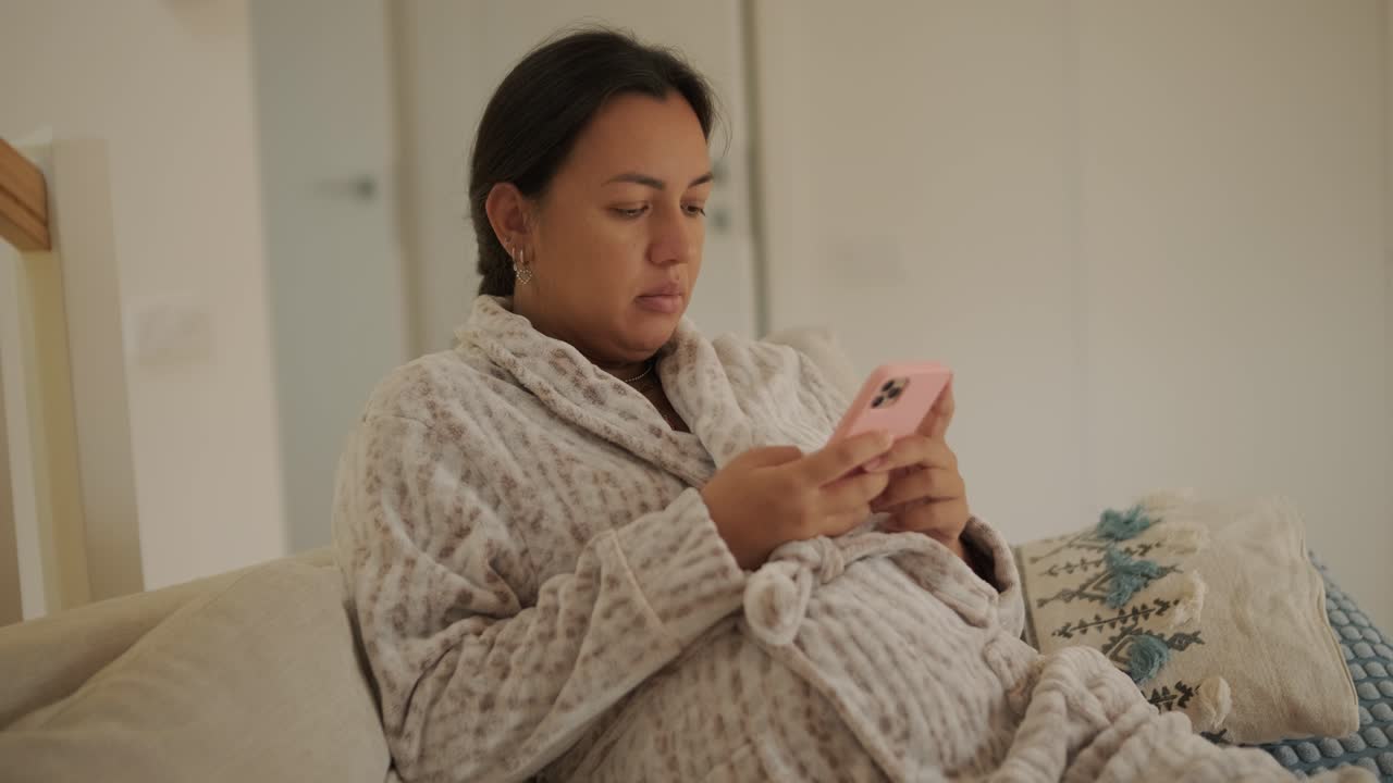 Una hermosa mujer embarazada sentada cómodamente en casa, disfrutando de videojuegos en una consola de TV. La escena combina relajación, entretenimiento moderno y maternidad en un ambiente acogedor.
