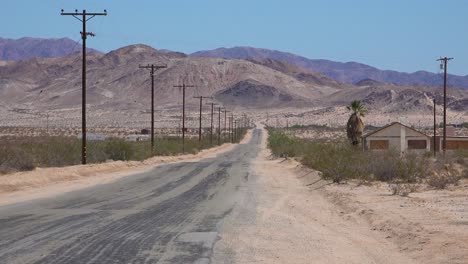 A-road-through-the-Mojave-desert-with-abandoned-houses-nearby