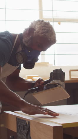 african american craftsman sands wood in a workshop