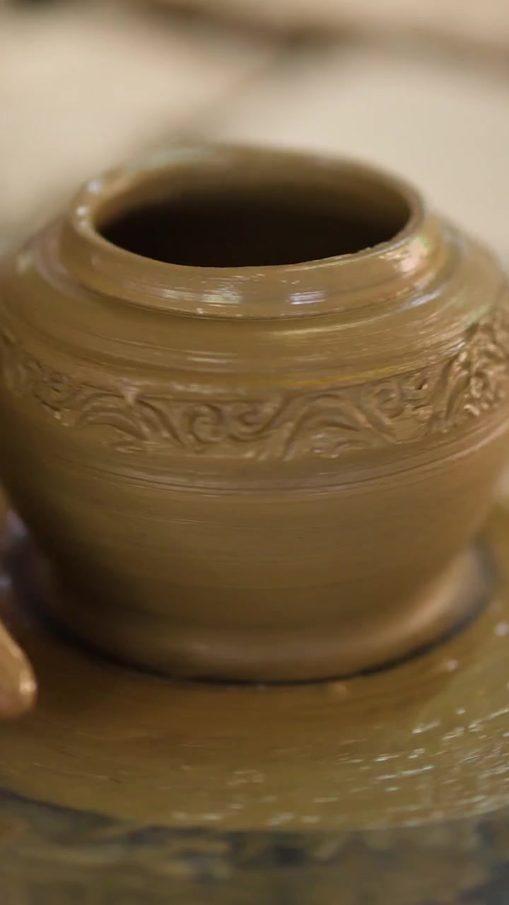 Primo piano delle mani di un vasaio che rifiniscono un vaso di argilla bagnata a Nonthaburi, Thailandia