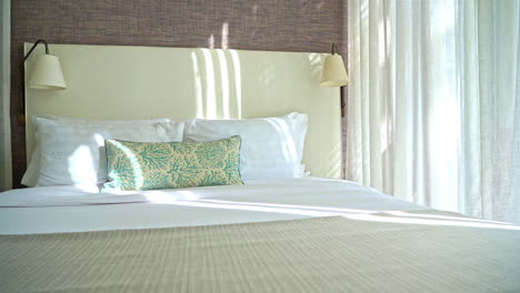 free bedroom interior with a bed with white pillows and comortable mattress near a window with curtains available for hotel guests