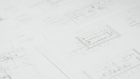 a hand holding a pen while working on architectural or engineering blueprints