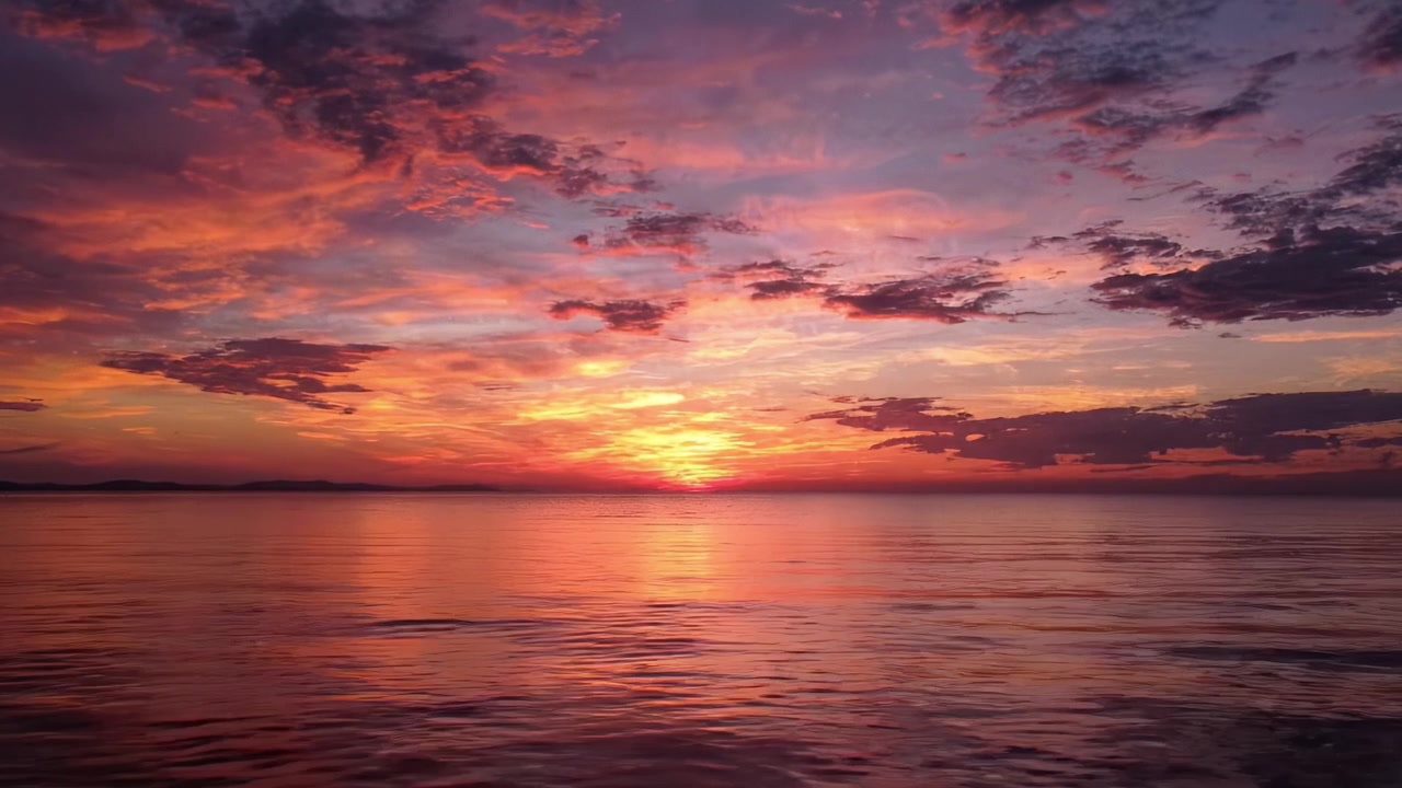 Matahari Terbenam yang Menakjubkan di Atas Perairan Tenang: Tampilan Warna yang Memukau Memantul di Permukaan Laut Saat Malam Menjelang