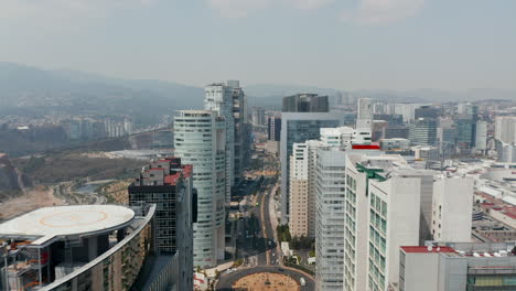 Forward-fly-above-street-leading-between-rows-of-tall-office-buildings.-Aerial-view-of-skyscrapers-in-Santa-Fe-district.-Mexico-City,-Mexico.