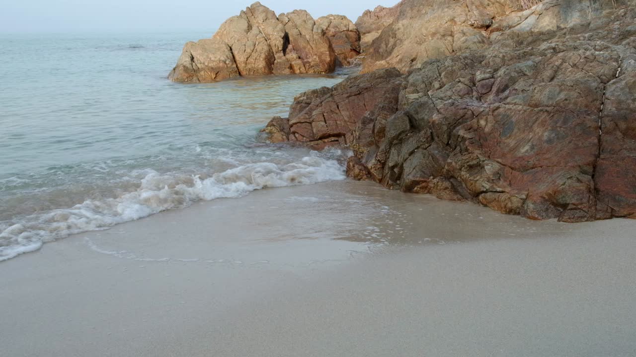 medium shot of beach and rocks with slow motion small wave