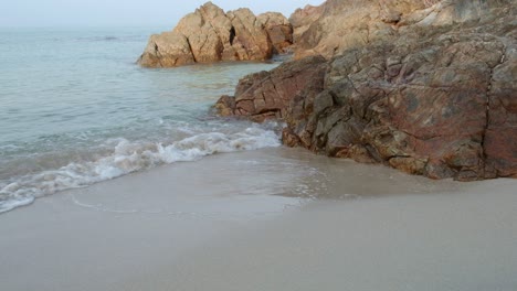 Mittlere-Aufnahme-Von-Strand-Und-Felsen-Mit-Kleiner-Welle-In-Zeitlupe