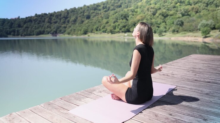 mujer practicando yoga junto al lago