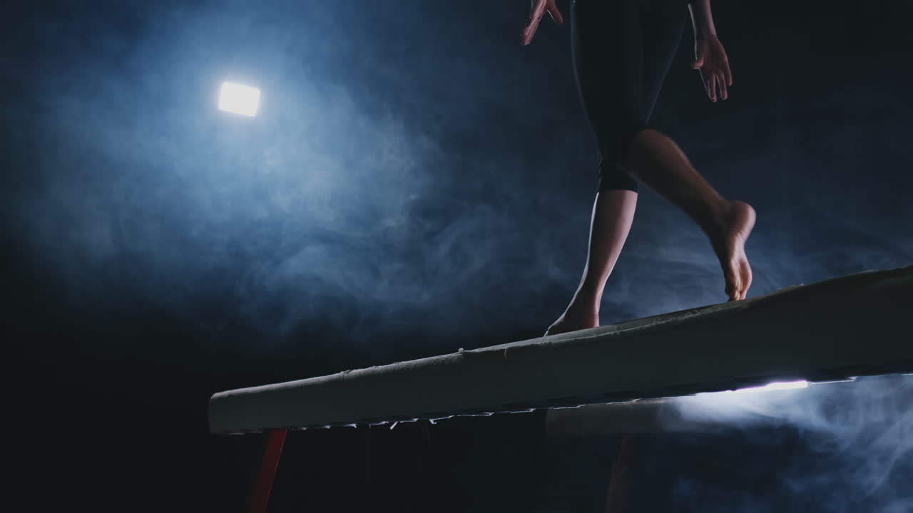 Close-up of the foot of a professional gymnast girl jumping in slow motion in the smoke on a balance beam. Women's gymnastics. Grace and a healthy lifestyle