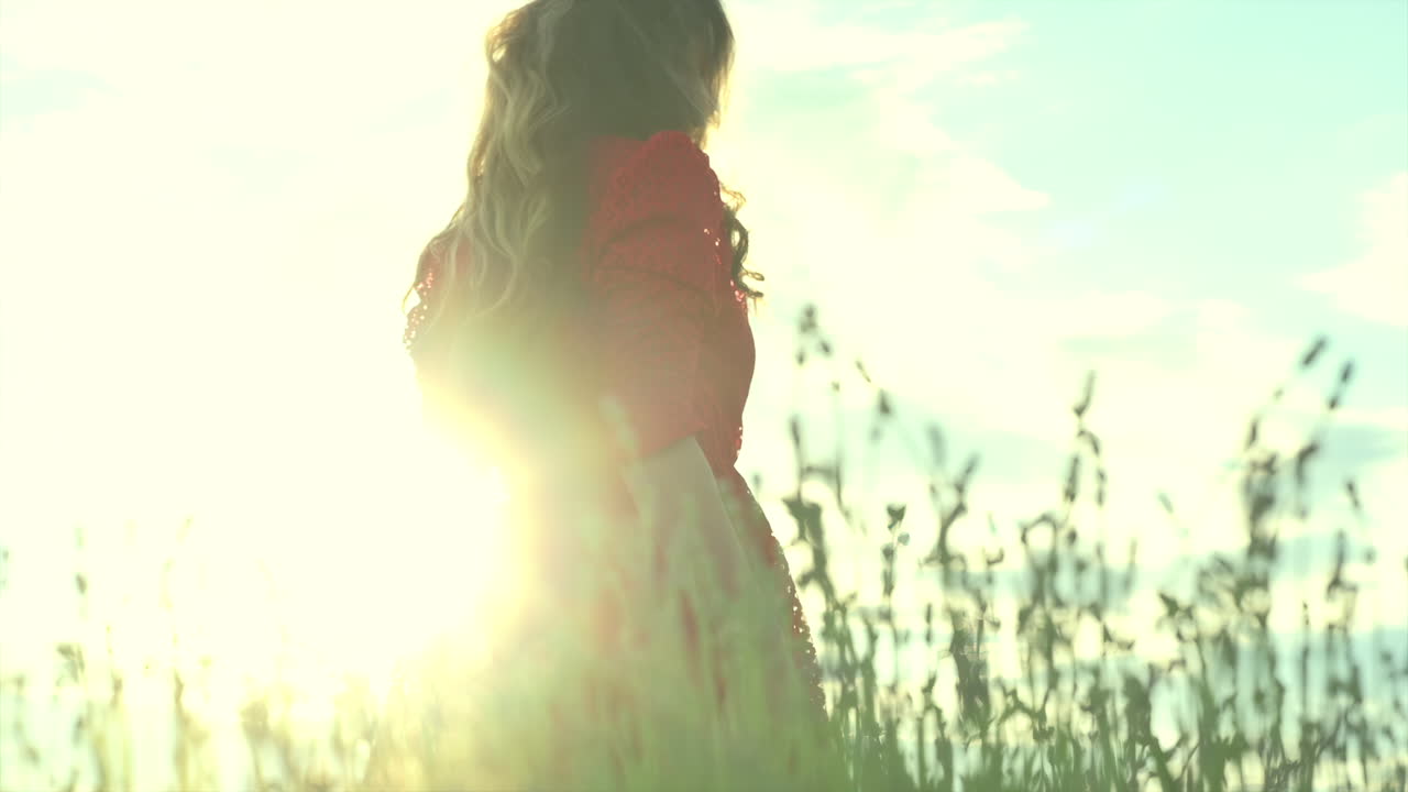 A young woman enjoys the sunlight as she smiles softly, surrounded by open skies and natural light