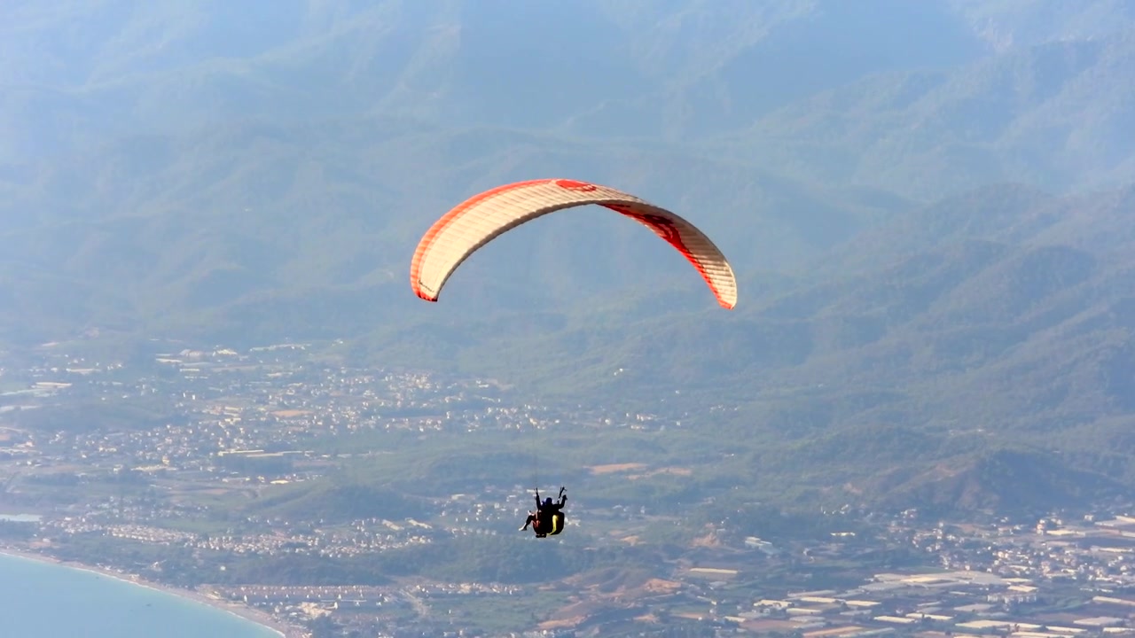 Tandem Paraglider Soaring Over Coastal Mountains and Sea