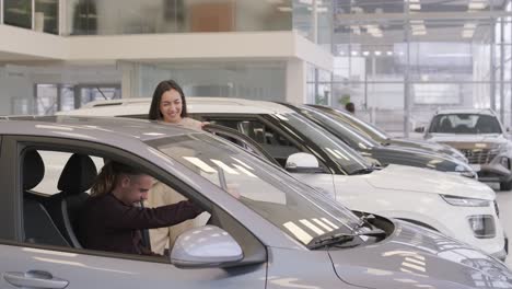 una hermosa pareja de jóvenes en la sala de exposición de automóviles eligiendo un coche nuevo para comprar.
