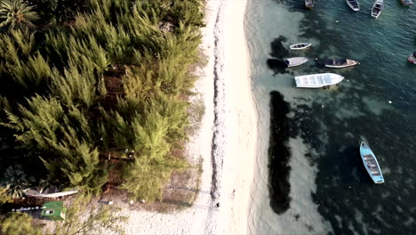 Aerial-birds-eye-shot-showing-sandy-beach-beside-clear-sea-and-speedboats