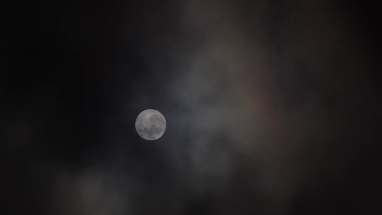 어두운 하늘에 보름달 앞을 구름이 지나간다