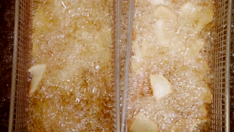 top down close-up of potato dippers deep fried in oil in baskets